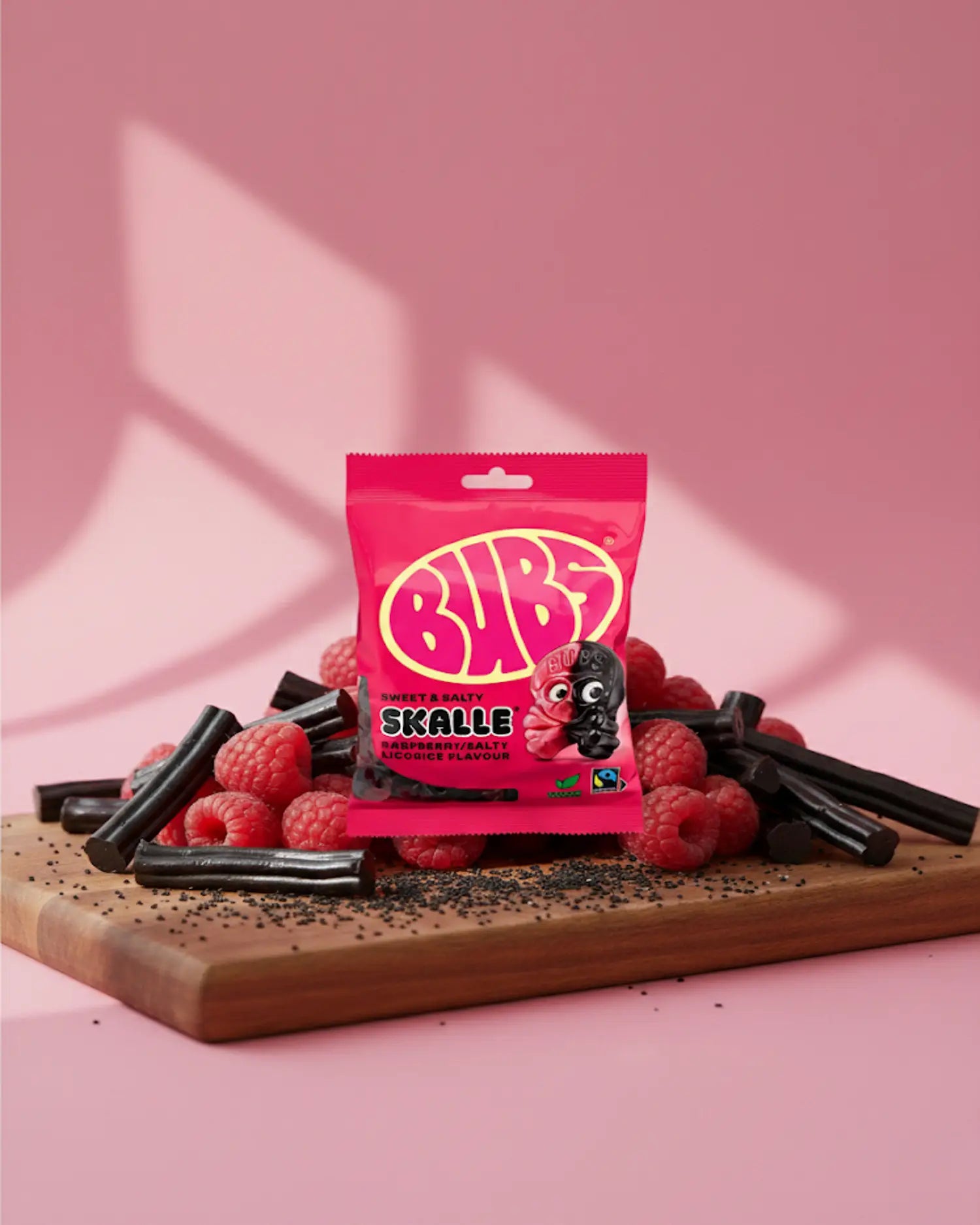 BUBS Swedish vegan candy - One Raspberry Liquorice Skull bag on a cutting board with rasberries and licorice 