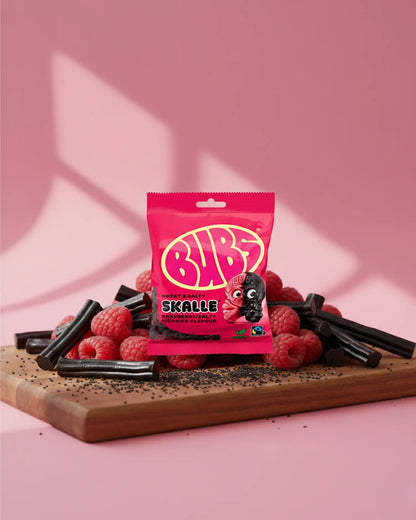 BUBS Swedish vegan candy - One Raspberry Liquorice Skull bag on a cutting board with rasberries and licorice 